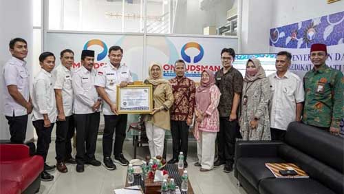Bupati Dharmasraya, Sutan Riska Tuanku Kerajaan, menerima sertifikat penghargaan, yang diserahkan Kepala Ombudsman RI Perwakilan Sumatera Barat, Yefri Hariani di Padang