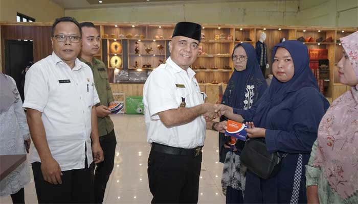 Asisten Perekonomian dan Pembangunan Setdakab Asahan, Oktoni Eriyanto, menyerahkan Buku Tabungan Dana Pinjaman Bergulir kepada Pelaku Usaha Mikro