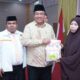 Penyerahan bantuan simbolis kepada penerima manfaat serta pemberian plakat kepada Bupati Asahan