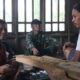 Agus duduk bersama warga lain dan Satgas TMMD Reguler ke-128 Kodim 0702/Purbalingga dengan dinding rumah baru