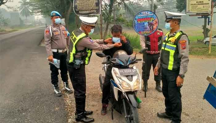 Personel Polres Dharmasraya Bagikan Masker kepada Masyarakat di Jalinsum Gunung Medan